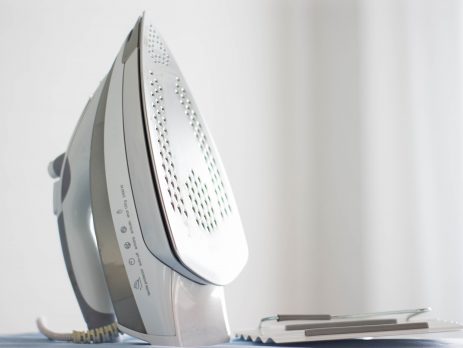 A white steam iron on an ironing board