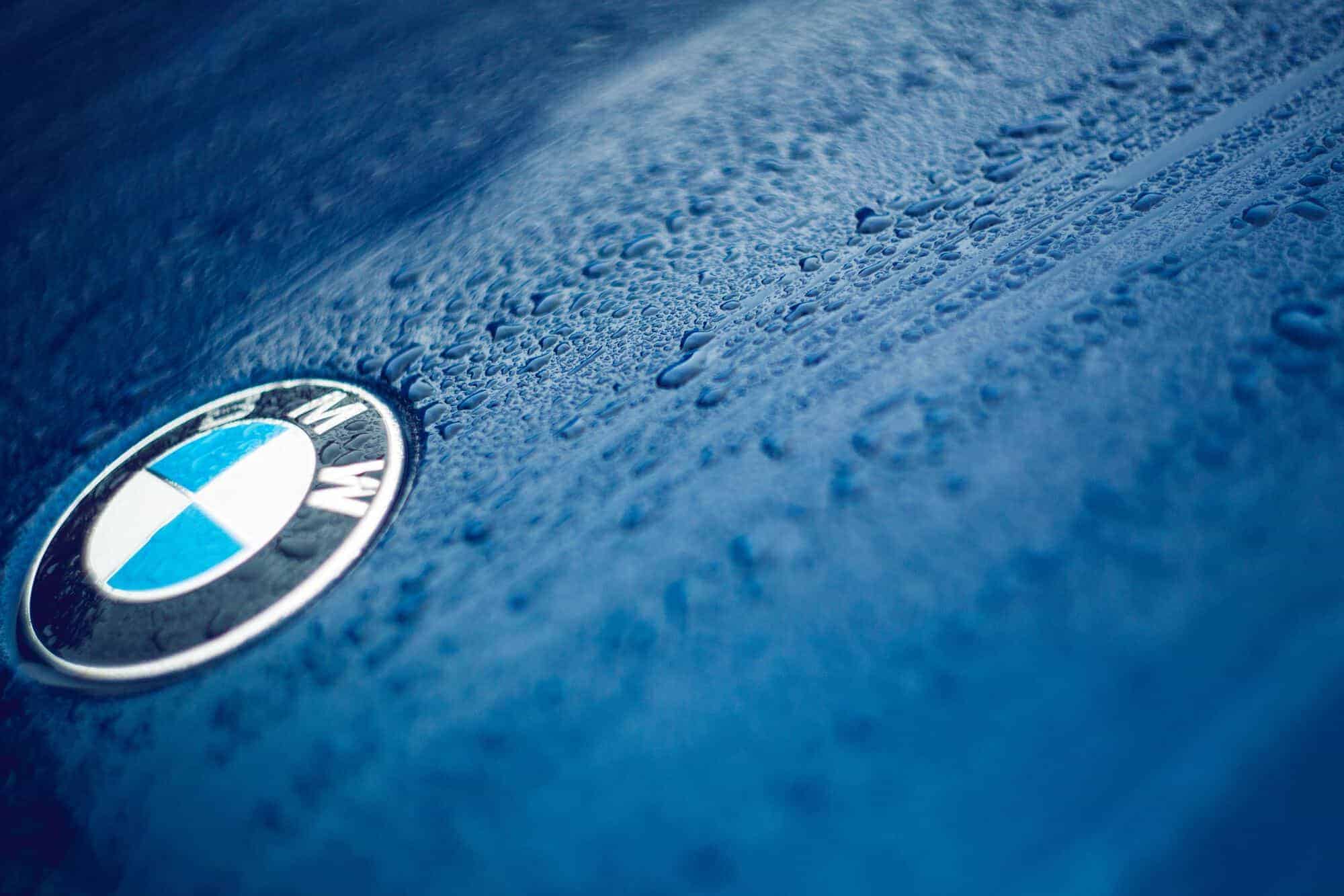Close up of car logo BMW on a wet blue bonnet 