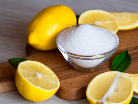 Cut lemons and a bowl of sugar on a board