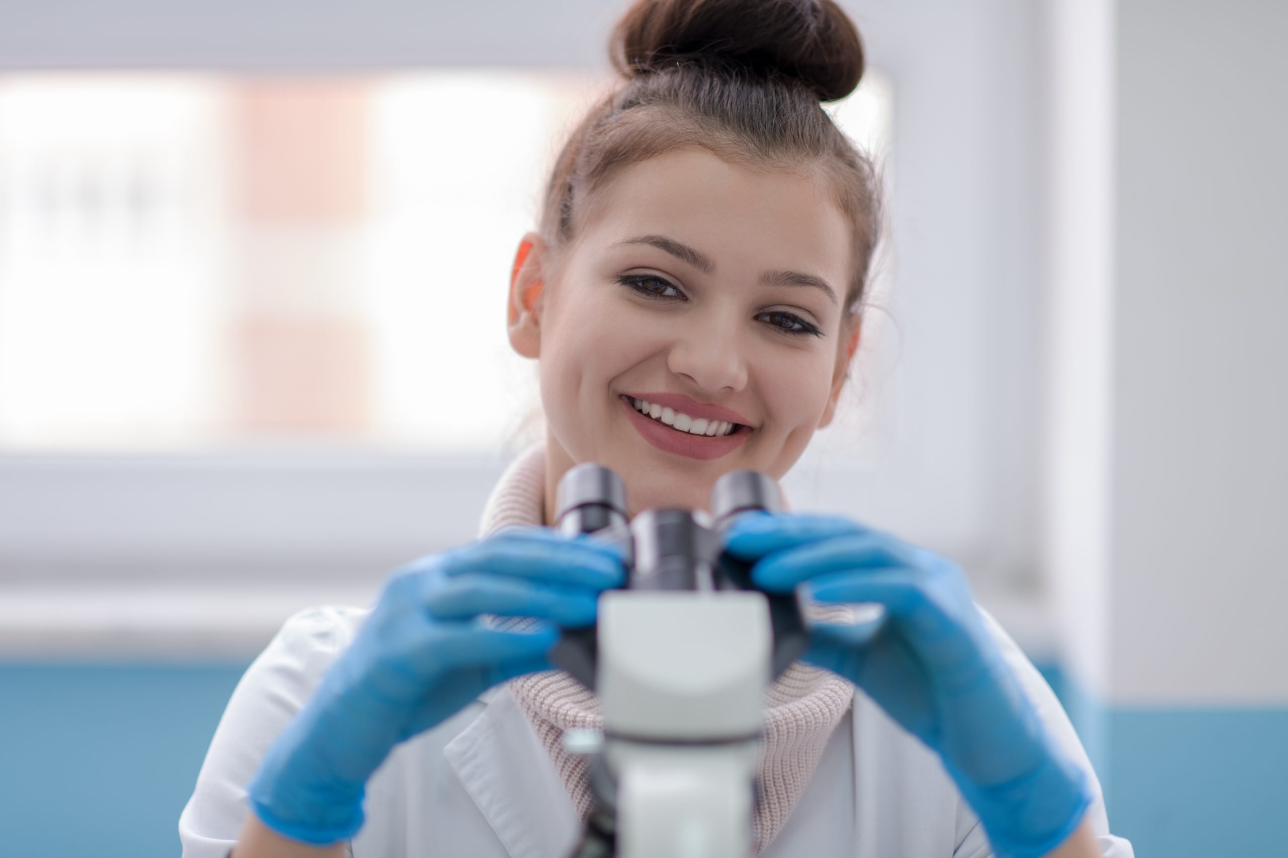 Smiling lab apprentice holding a microscope