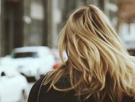 A blonde haired woman walking in the street