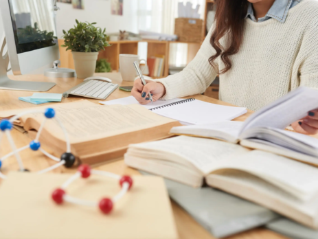 Cropped image of student reading books and taking notes