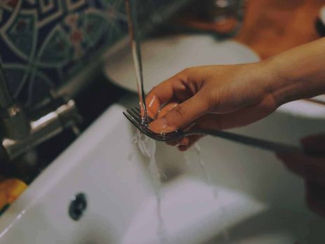 Cleaning cutlery in a white sink