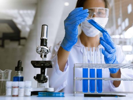 Chemistry student analysing test tubes in science lab