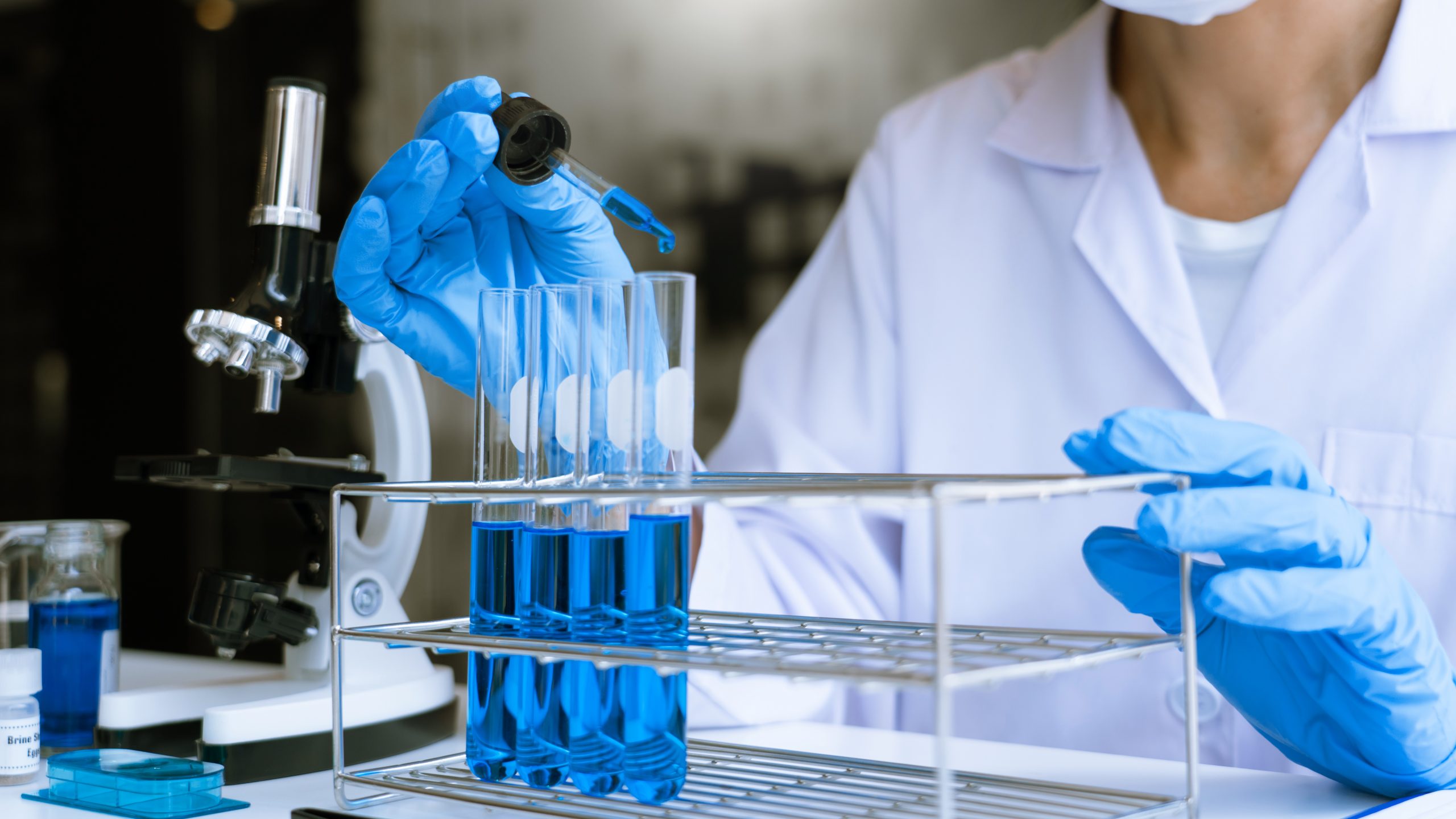 Scientist in lab wear doing investigations with test tubes in experiment