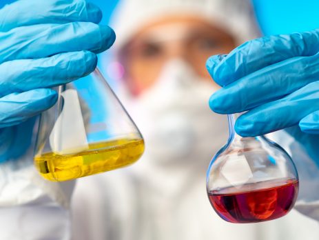 Scientist holding two beakers of different coloured chemicals