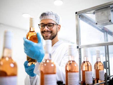Technician checking the quality of bottled wine in a bottling factory.