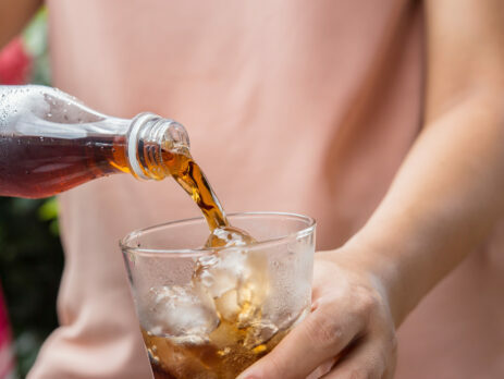 Cola being poured into a glass filled with ice