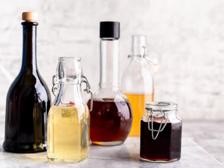 Different shaped glasses bottles containing different types of vinegar.