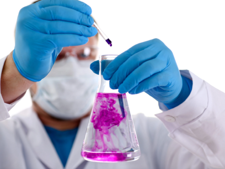 A chemist holds test tube of glass containing a liquid solution of potassium permanganate while conducting an analysis of water samples.