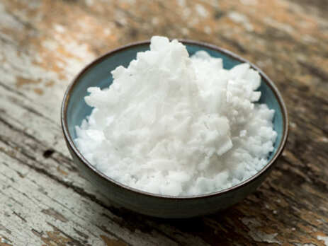 A bowl of solid, white crystal potassium hydroxide
