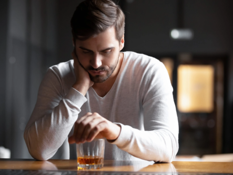 Man sitting at a bar drinking whiskey