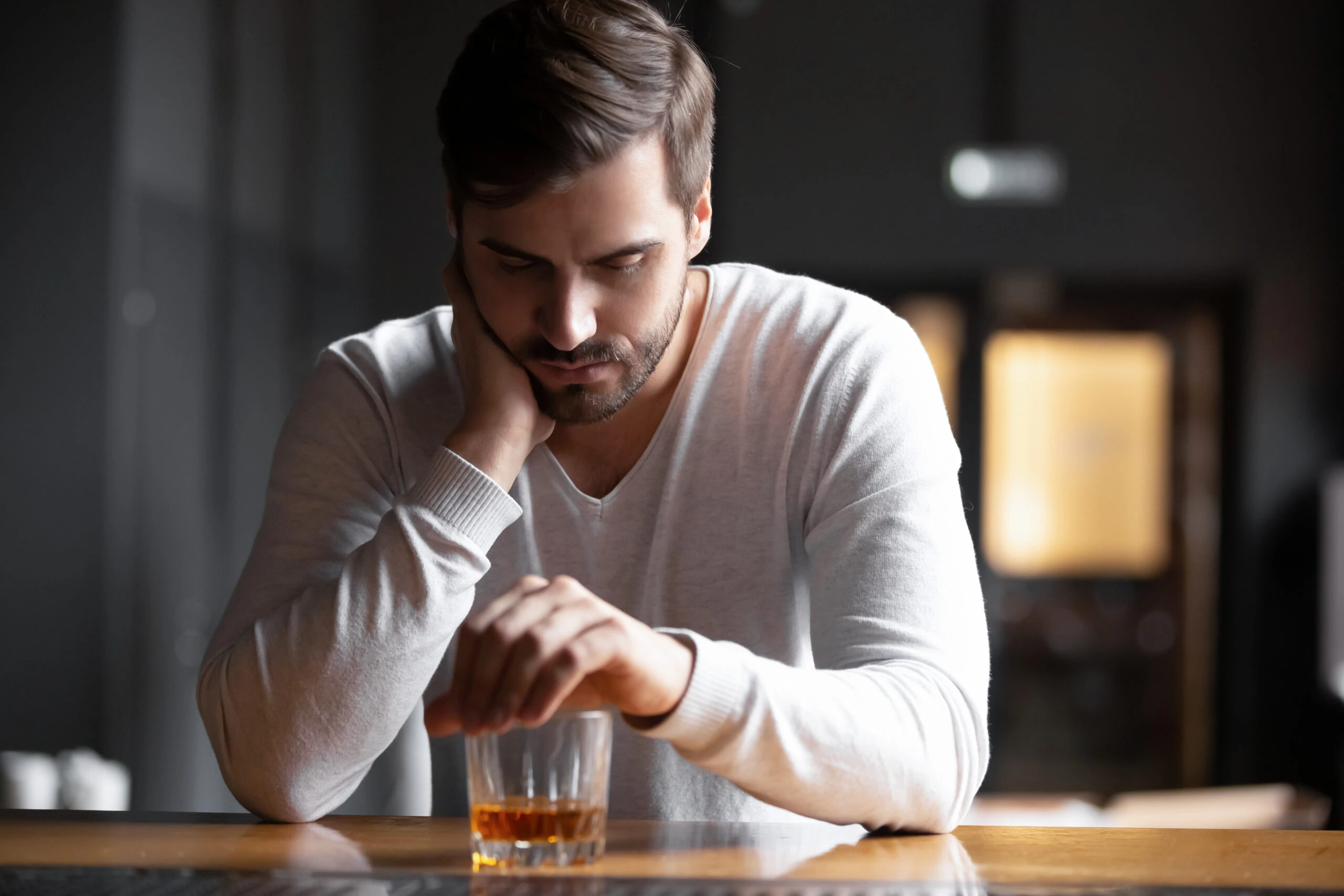 Man sitting at a bar drinking whiskey