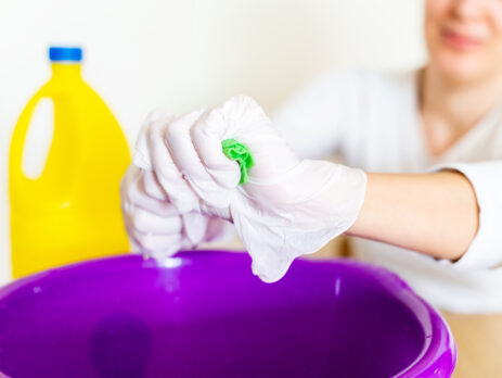 Cleaner wringing out a cloth into a bucket after using bleach