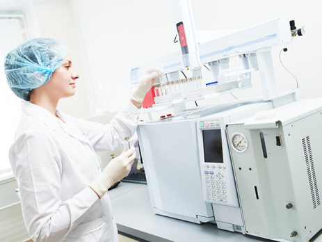 Scientific researcher placing a test tube into a chromatography machine.