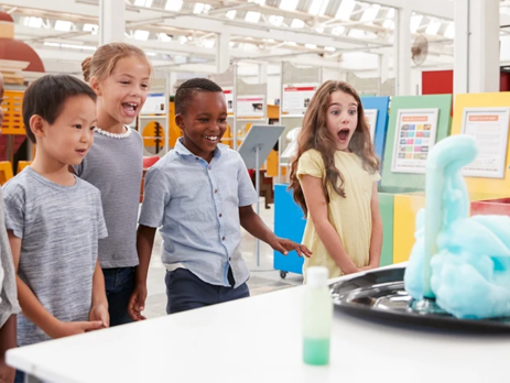A group of children in an exhibition watch a chemical science experiment.