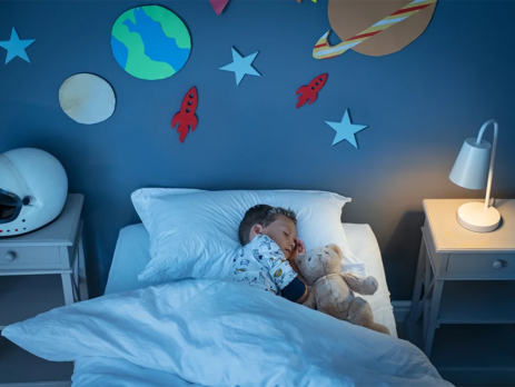 A child sleeps in a space-themed bedroom.