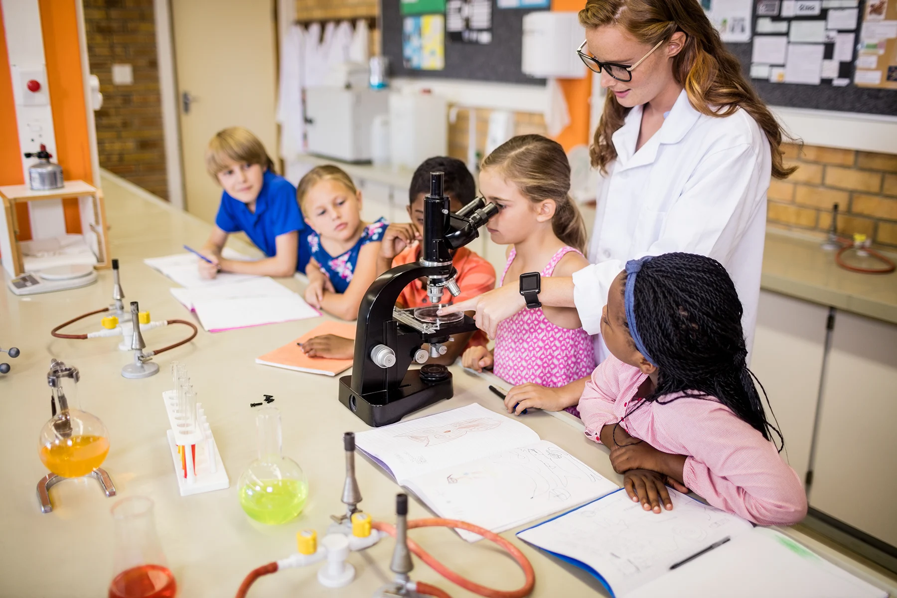 Science teacher teaching her students with a microscope
