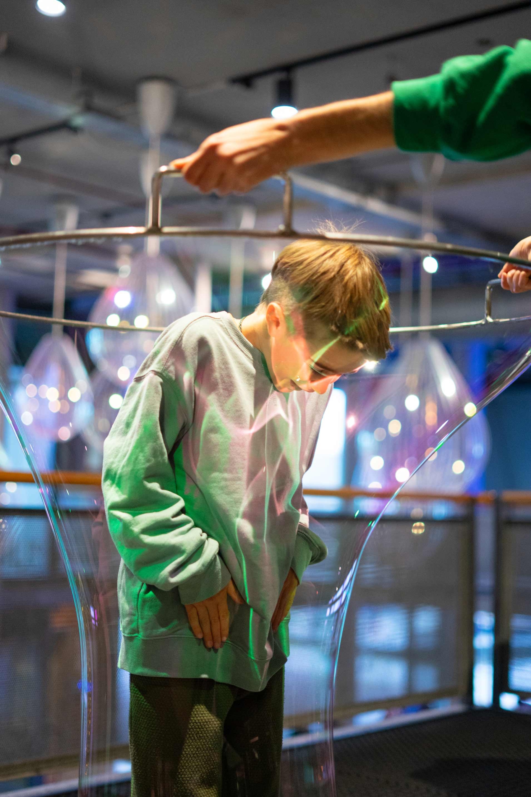 A young child experimenting with a giant soap bubble at a science museum