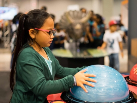 A young girl interacting with a semi sphere at a science museum