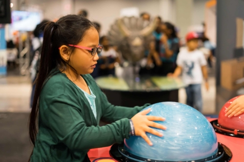 A young girl interacting with a semi sphere at a science museum