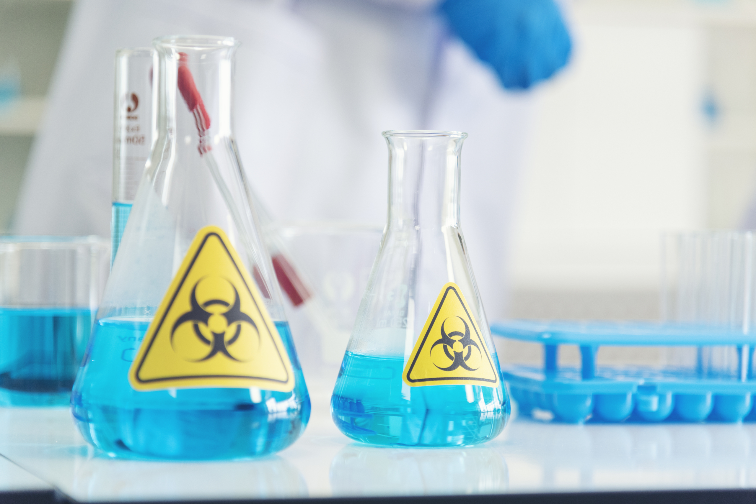 Beakers with blue chemicals and biohazard stickers
