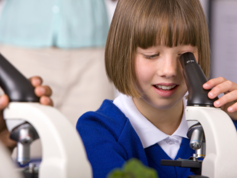 Young girl using a microscope in science class
