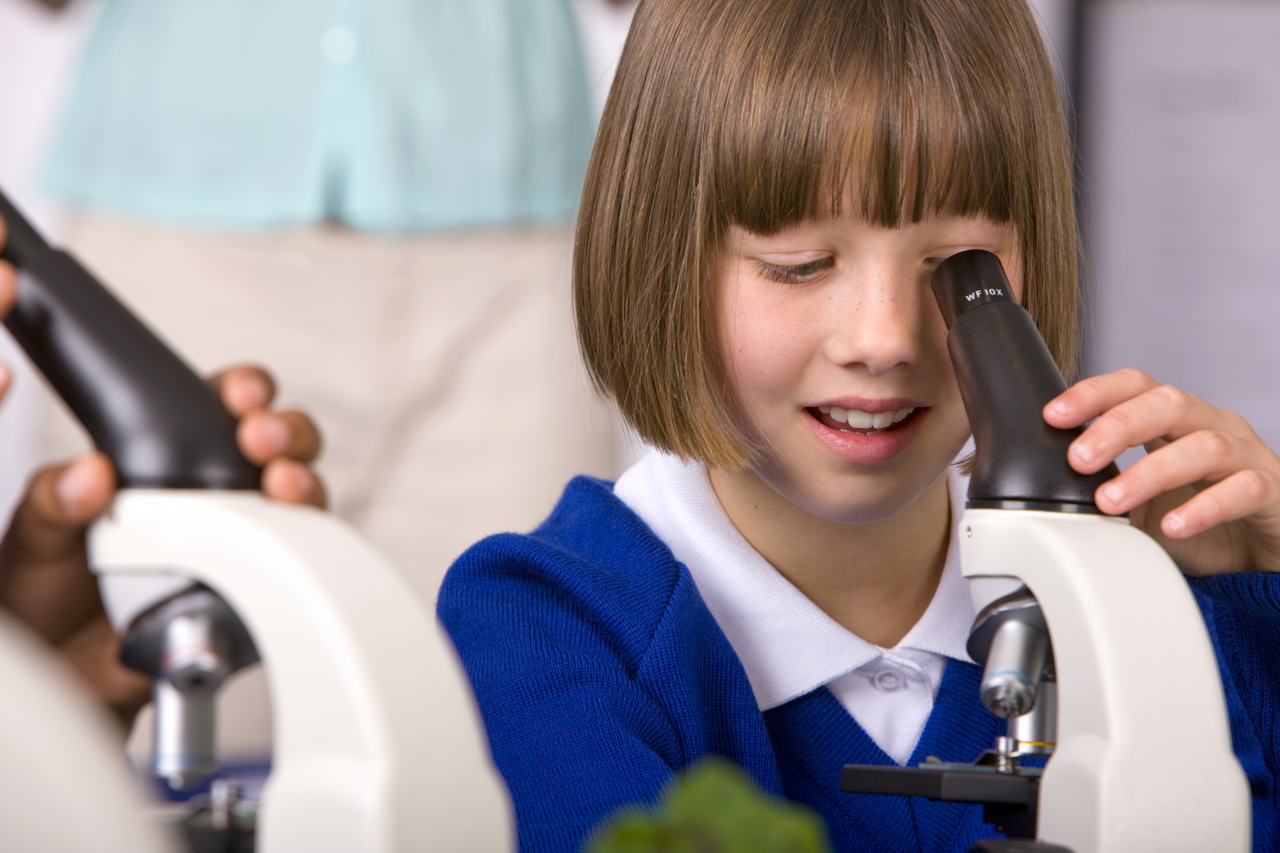 Young girl using a microscope in science class