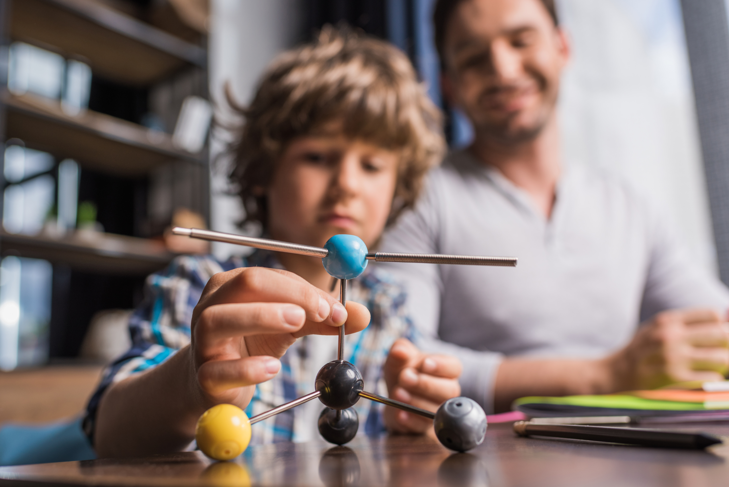 Father and son examining a model of a atom