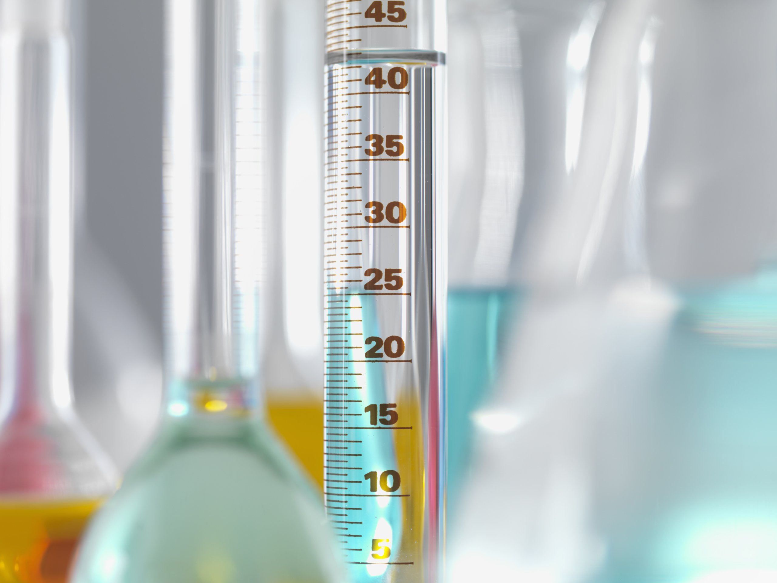 Thermometer surrounded by chemistery beakers