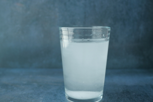 Glass of water with dissolved, cloudy substance in it